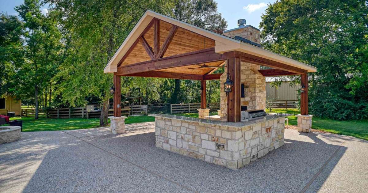 Image of an outdoor living pavillion with stone fire place and outdoor kitchen by Wonderview Custom Homes