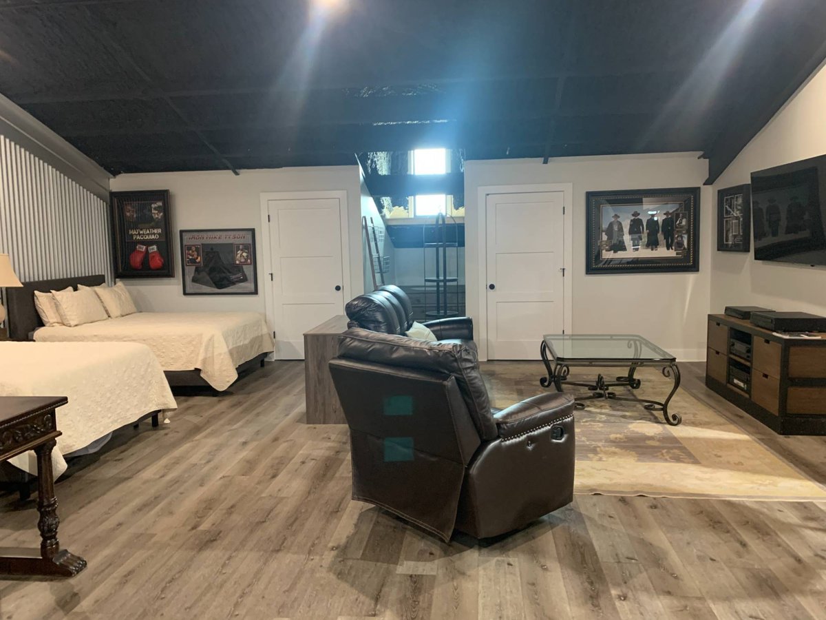 Large residential barndominium lounge by Wonderview Home Services in Navasota, TX with entertainment area and guest beds.-optimized