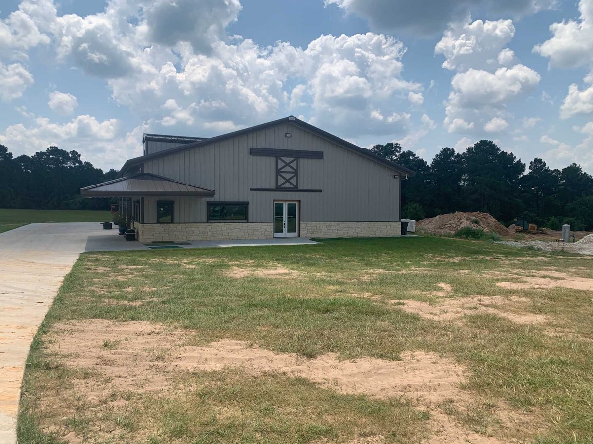 Rear exterior view of a residential barndominium by Wonderview Home Services in Navasota, TX with metal siding and expansive yar-optimized