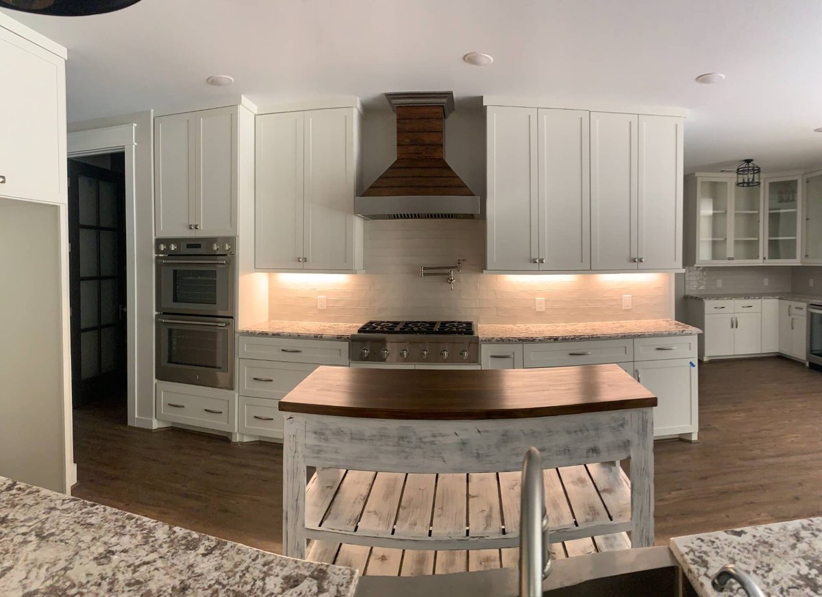 Elegant open-concept kitchen designed by Wonderview Home Services in Magnolia, TX with white cabinetry and granite counters.-optimized