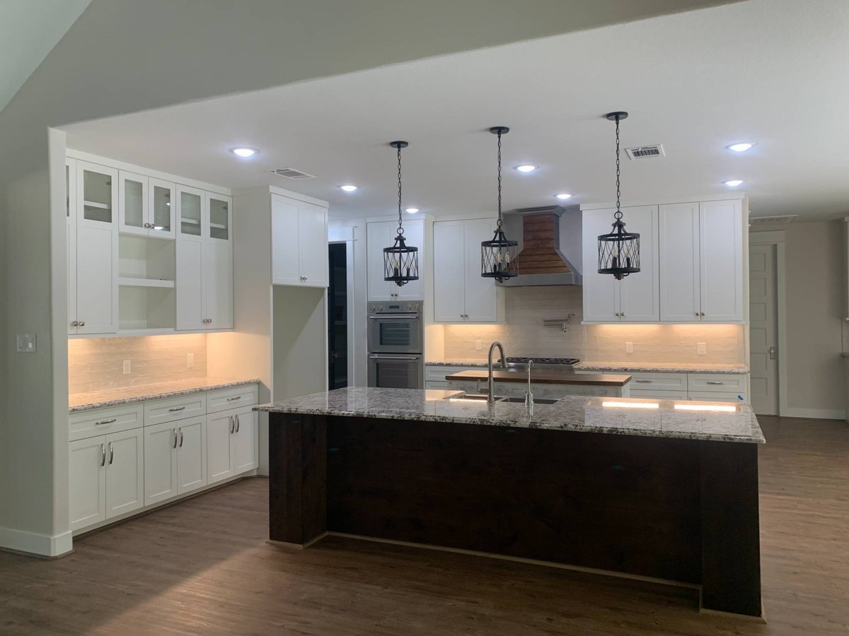 Modern custom kitchen by Wonderview Home Services in Magnolia, TX with white cabinetry and oversized granite island.-optimized
