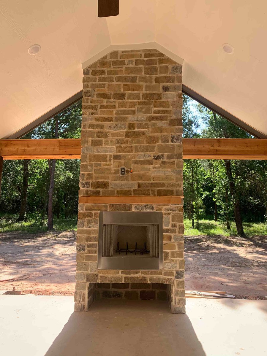 Outdoor stone fireplace built by Wonderview Home Services for a residential new construction home in Magnolia, TX.