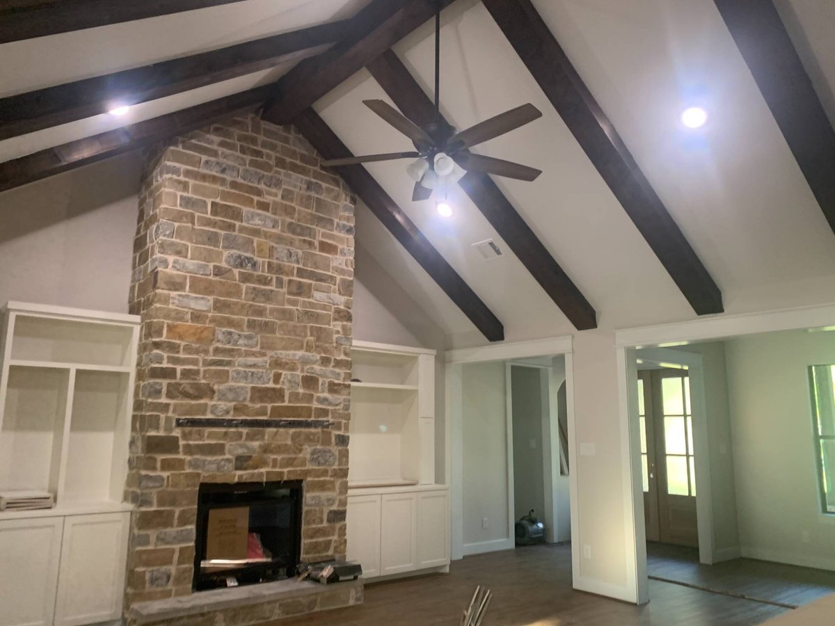 Vaulted living room in a Wonderview Home Services residential new construction home in Magnolia, TX with exposed wood beams and -optimized