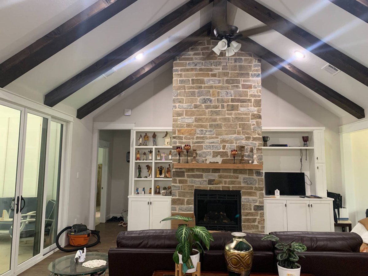 Vaulted living room with stone fireplace in a Wonderview Home Services residential new construction home in Magnolia, TX.-optimized