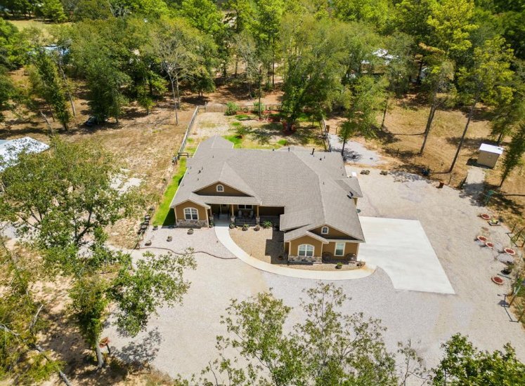 Aerial view of a custom residential home by Wonderview Home Services surrounded by wooded acreage in Magnolia, TX.-optimized
