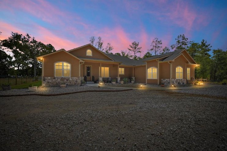 Evening exterior view of a custom home by Wonderview Home Services illuminated at sunset in Magnolia, TX.-optimized
