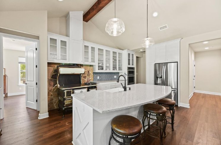 Luxury kitchen interior with white cabinets and rustic stove surround in a Magnolia, TX custom home by Wonderview Home Services.-optimized