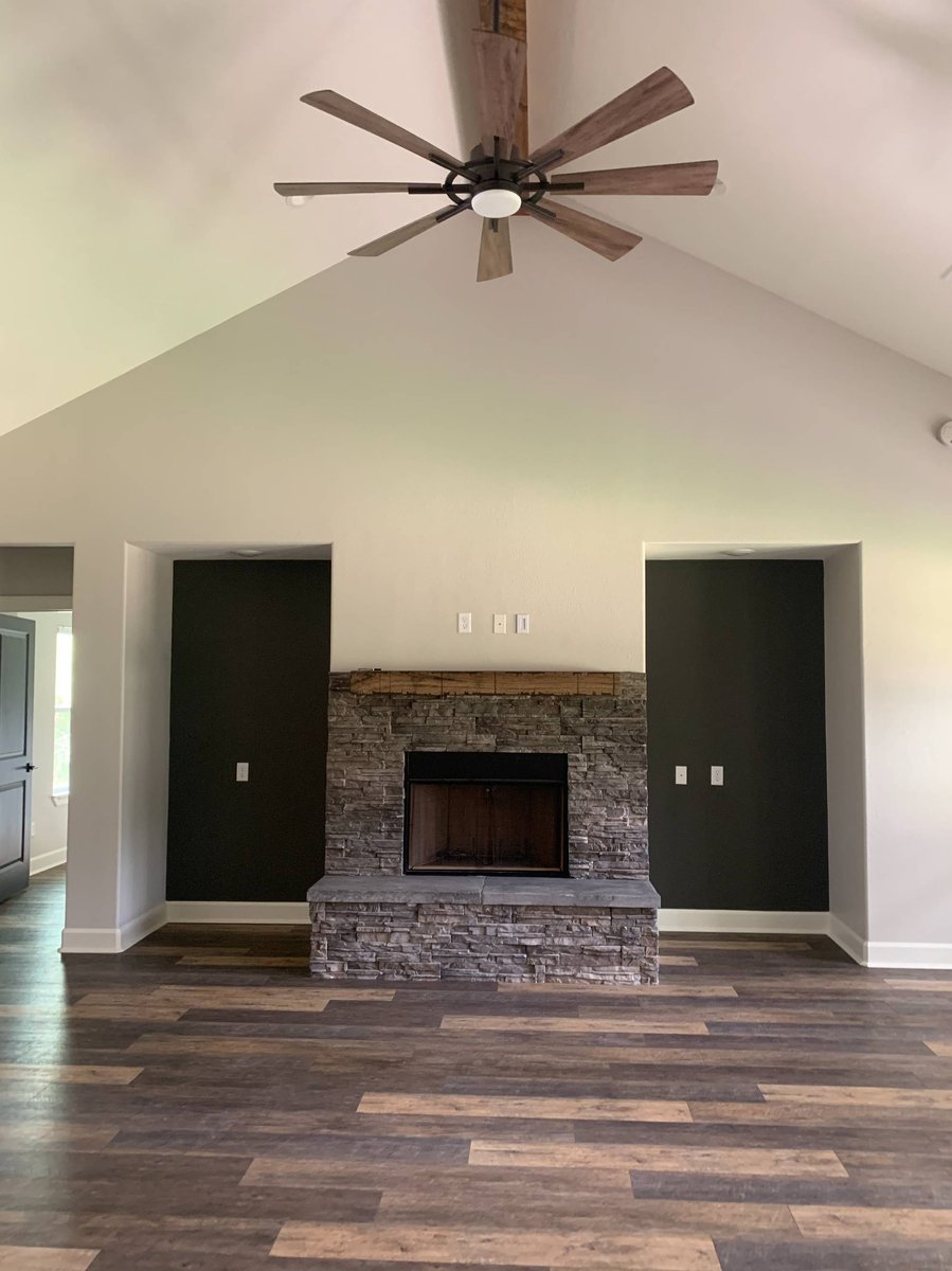 Open-concept living room with vaulted ceilings and stone fireplace by Wonderview Home Services in Magnolia, TX.-optimized