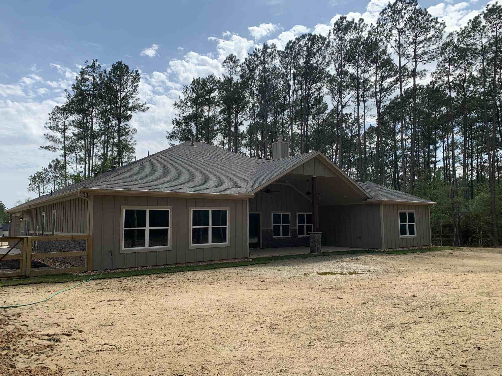 Rear exterior of a residential new construction home by Wonderview Home Services surrounded by pine trees in Magnolia, TX.