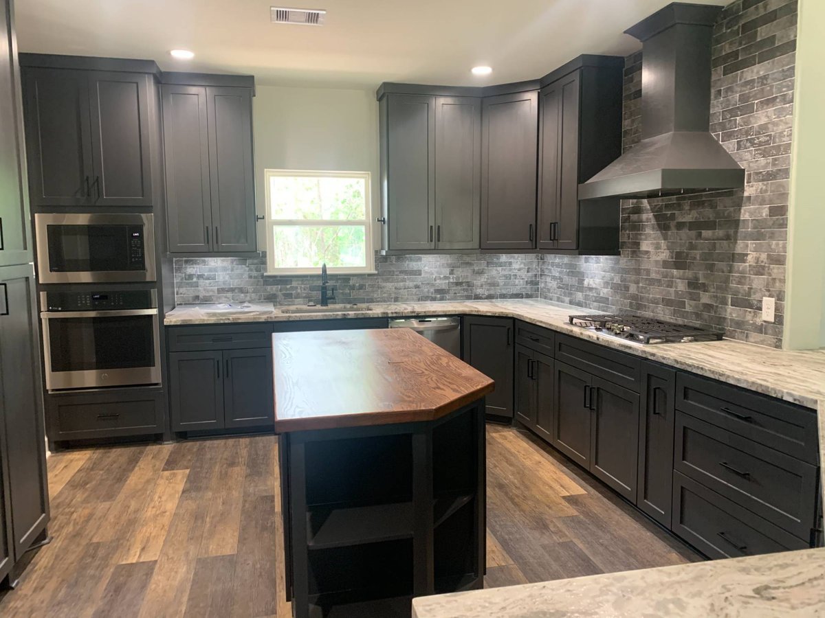 Residential new construction kitchen featuring large island and stone tile backsplash in Magnolia, TX.-optimized