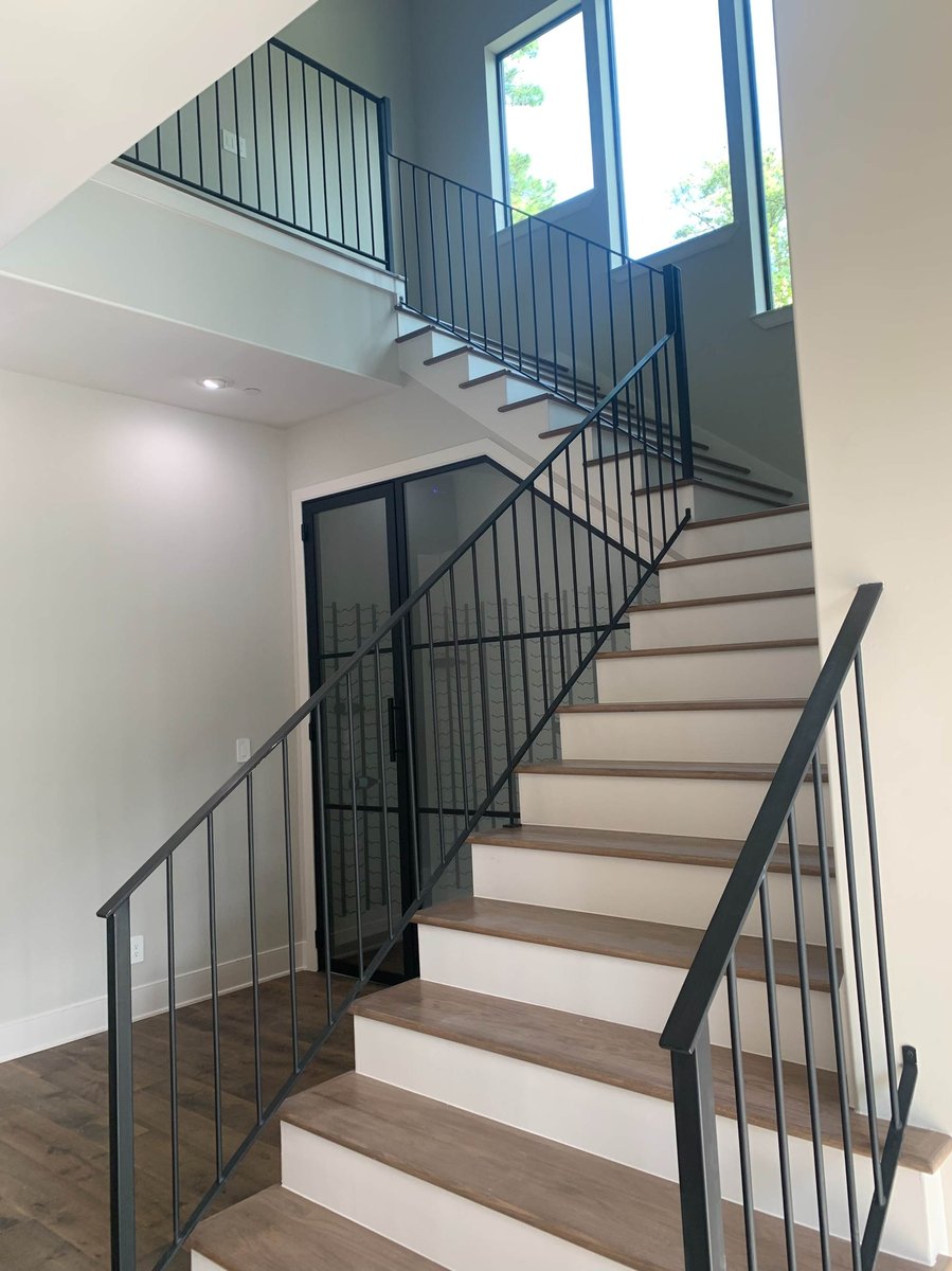 Modern staircase with black metal railing and floor-to-ceiling windows by Wonderview Home Services in Houston, TX.-optimized