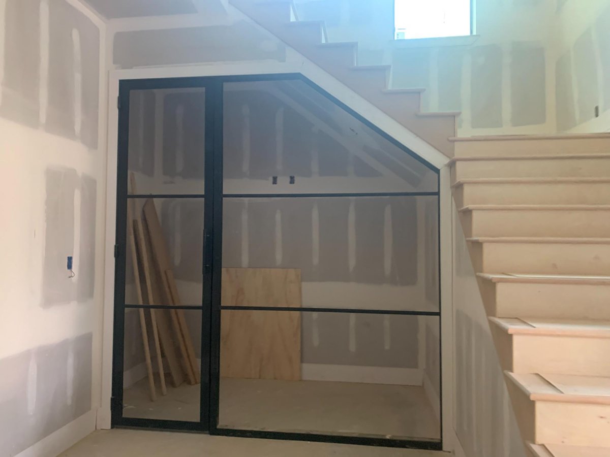 Modern staircase with glass-enclosed wine room under construction by Wonderview Home Services in Houston, TX.-optimized