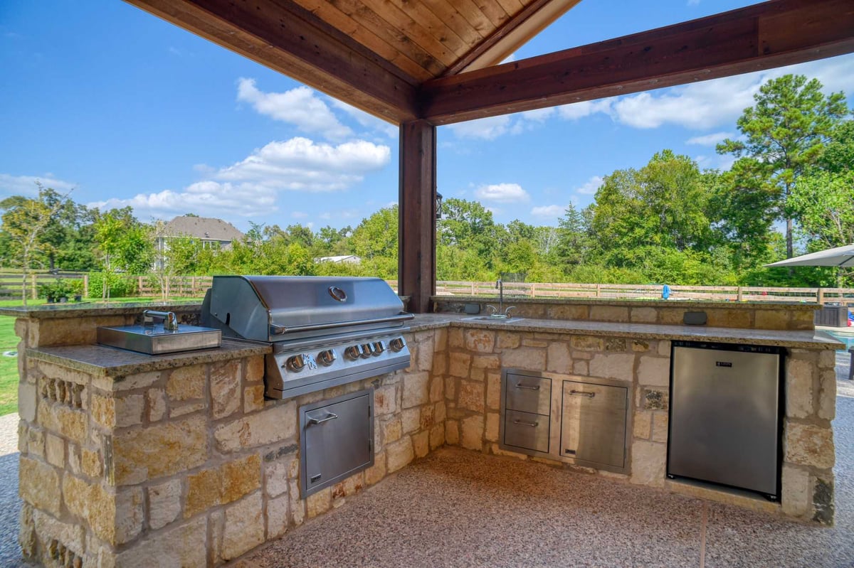 Built-in outdoor kitchen with stone counters and stainless steel grill by Wonderview Home Services in Montgomery, TX.-optimized