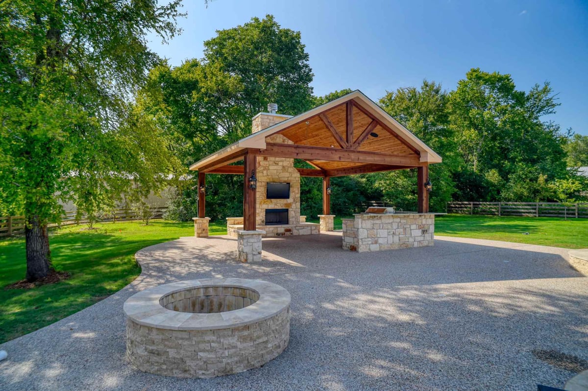 Covered outdoor patio with custom stone kitchen and fireplace by Wonderview Home Services in Montgomery, TX.-optimized