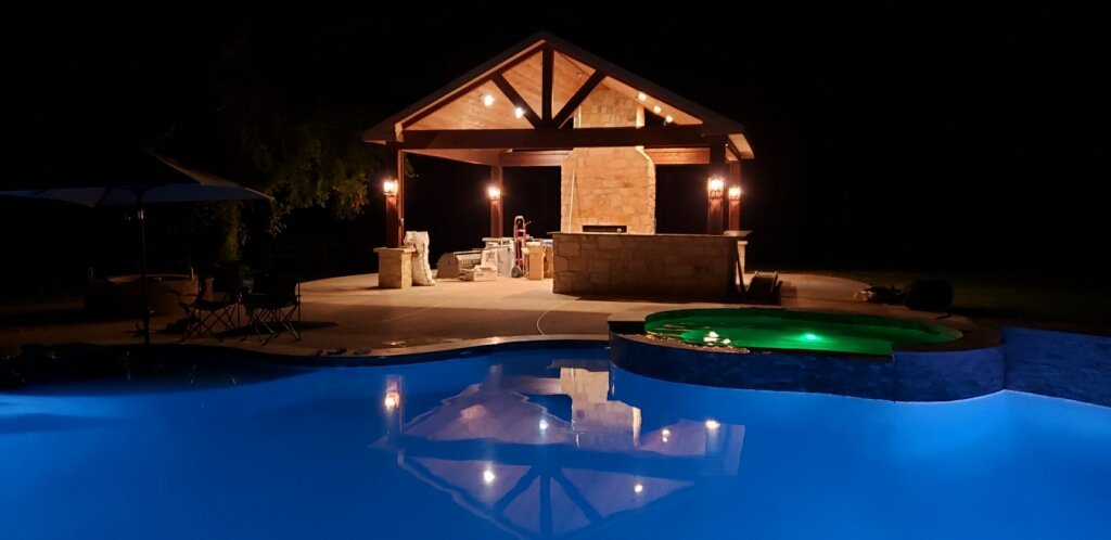 Luxury outdoor patio and pool pavilion illuminated at night by Wonderview Home Services in Montgomery, TX.-optimized