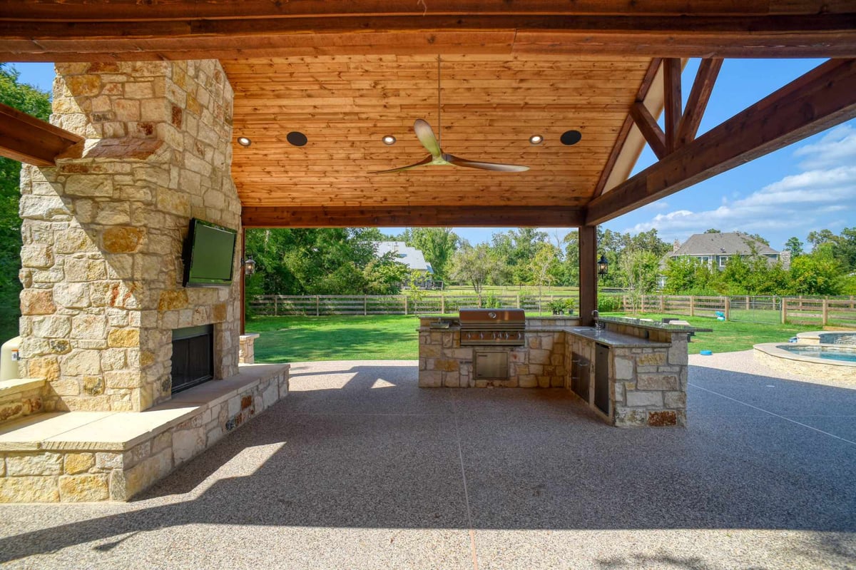 Spacious outdoor patio with stone fireplace and built-in grill by Wonderview Home Services in Montgomery, TX.-optimized
