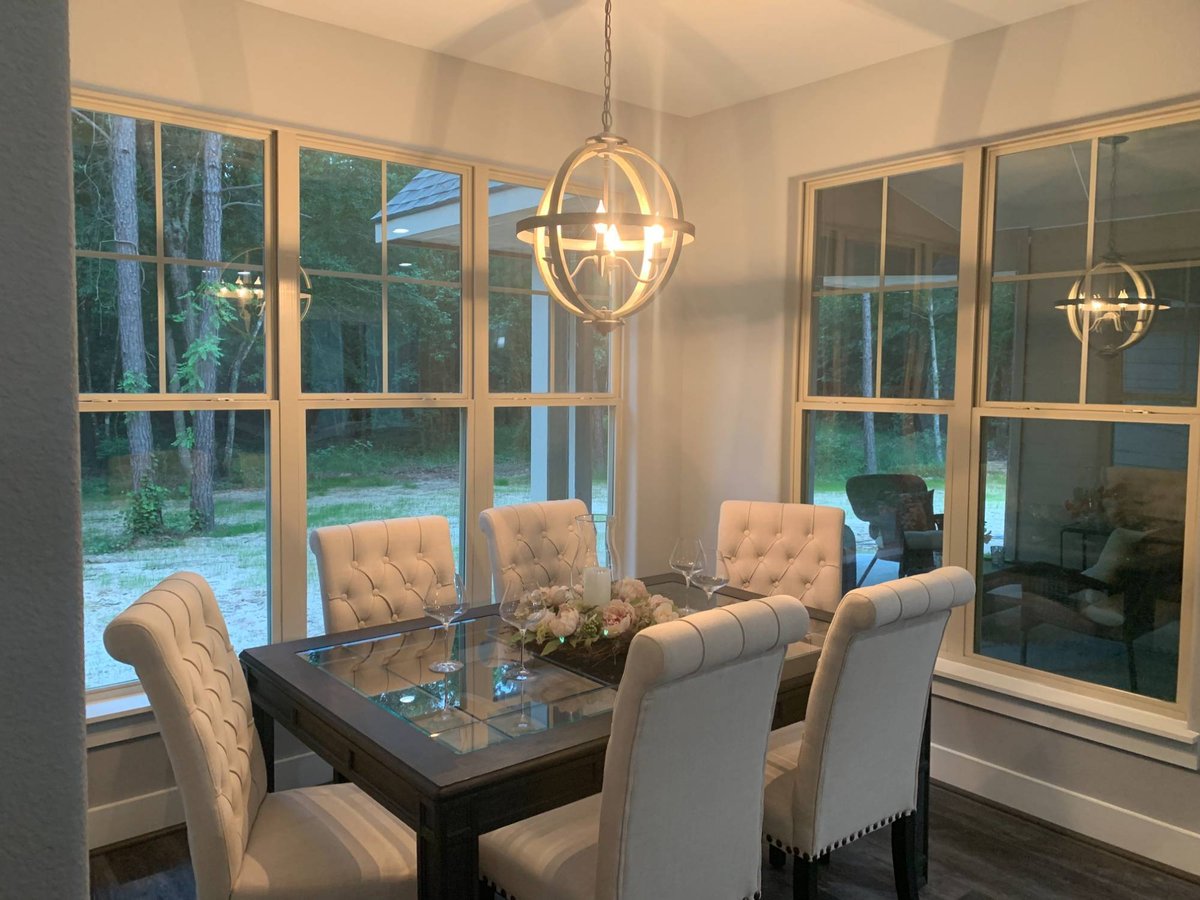 Elegant dining room with large windows and modern chandelier in a custom home by Wonderview Home Services in New Waverly, TX.-optimized