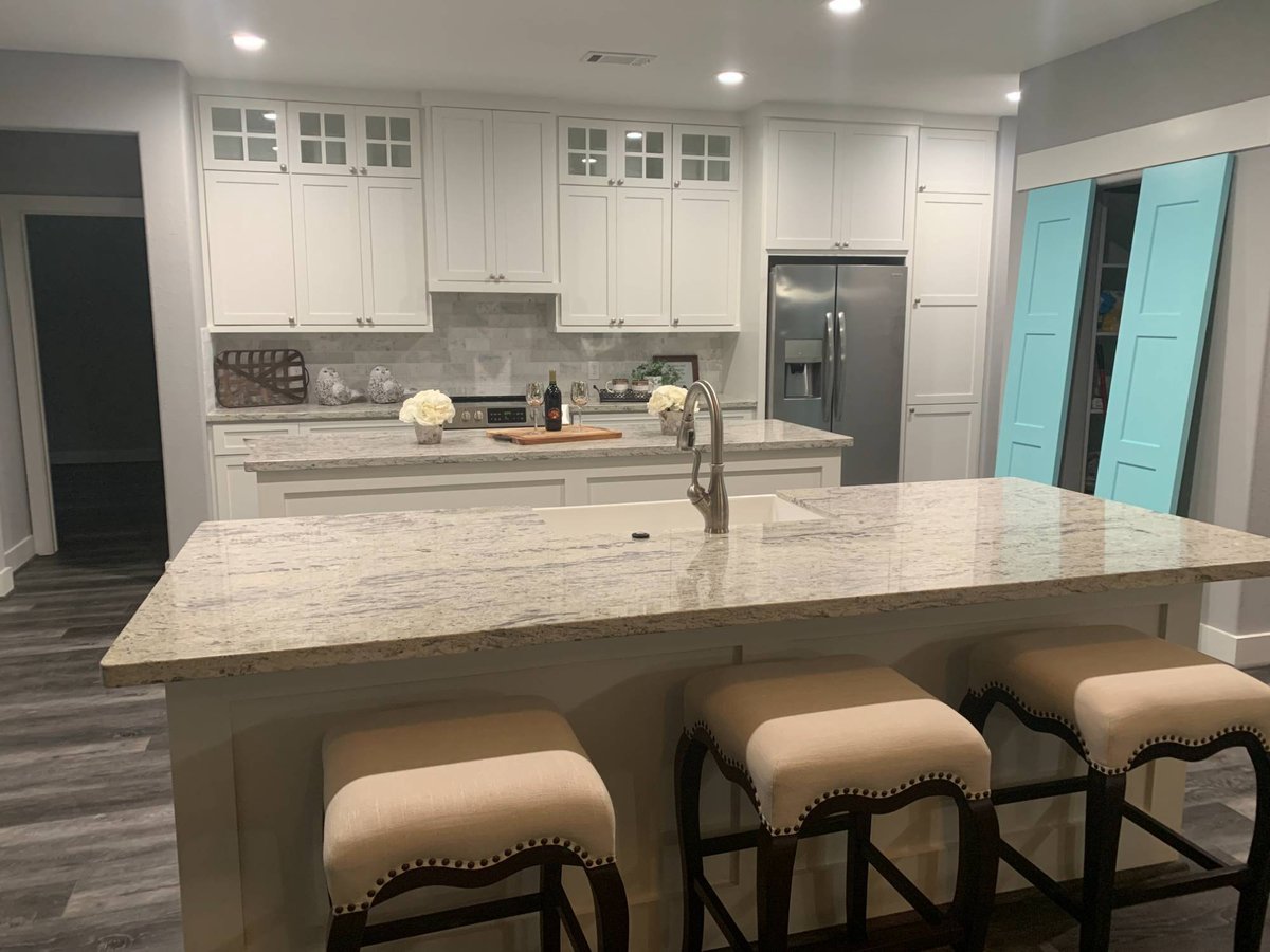 Modern custom kitchen with granite island and white cabinetry by Wonderview Home Services in New Waverly, TX.-optimized