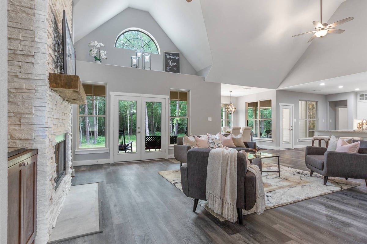 Open-concept living room with vaulted ceilings and stone fireplace in a custom home by Wonderview Home Services in New Waverly, -optimized