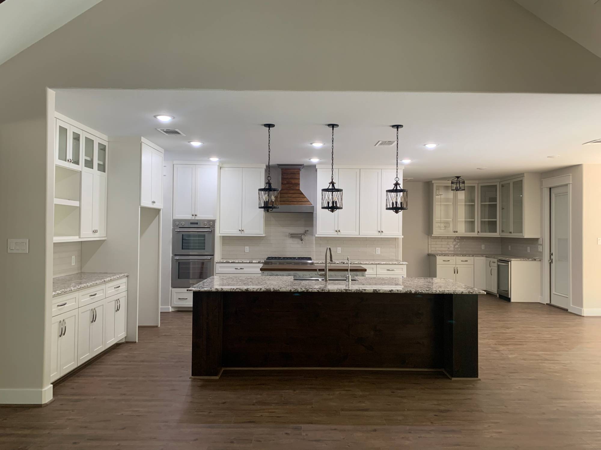 Residential new construction kitchen in Magnolia, Texas by Wonderview Home Services with custom white cabinets and wood flooring-optimized