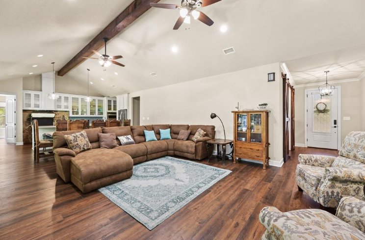 Large open living room with vaulted ceiling and sectional sofa in a custom home by Wonderview Home Services in Magnolia, TX.-optimized