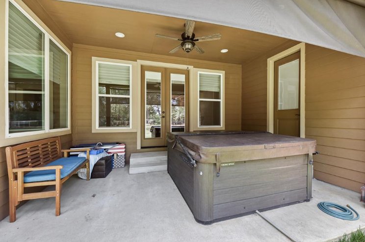Outdoor living space with hot tub and covered seating area in a Magnolia, TX custom home by Wonderview Home Services.-optimized