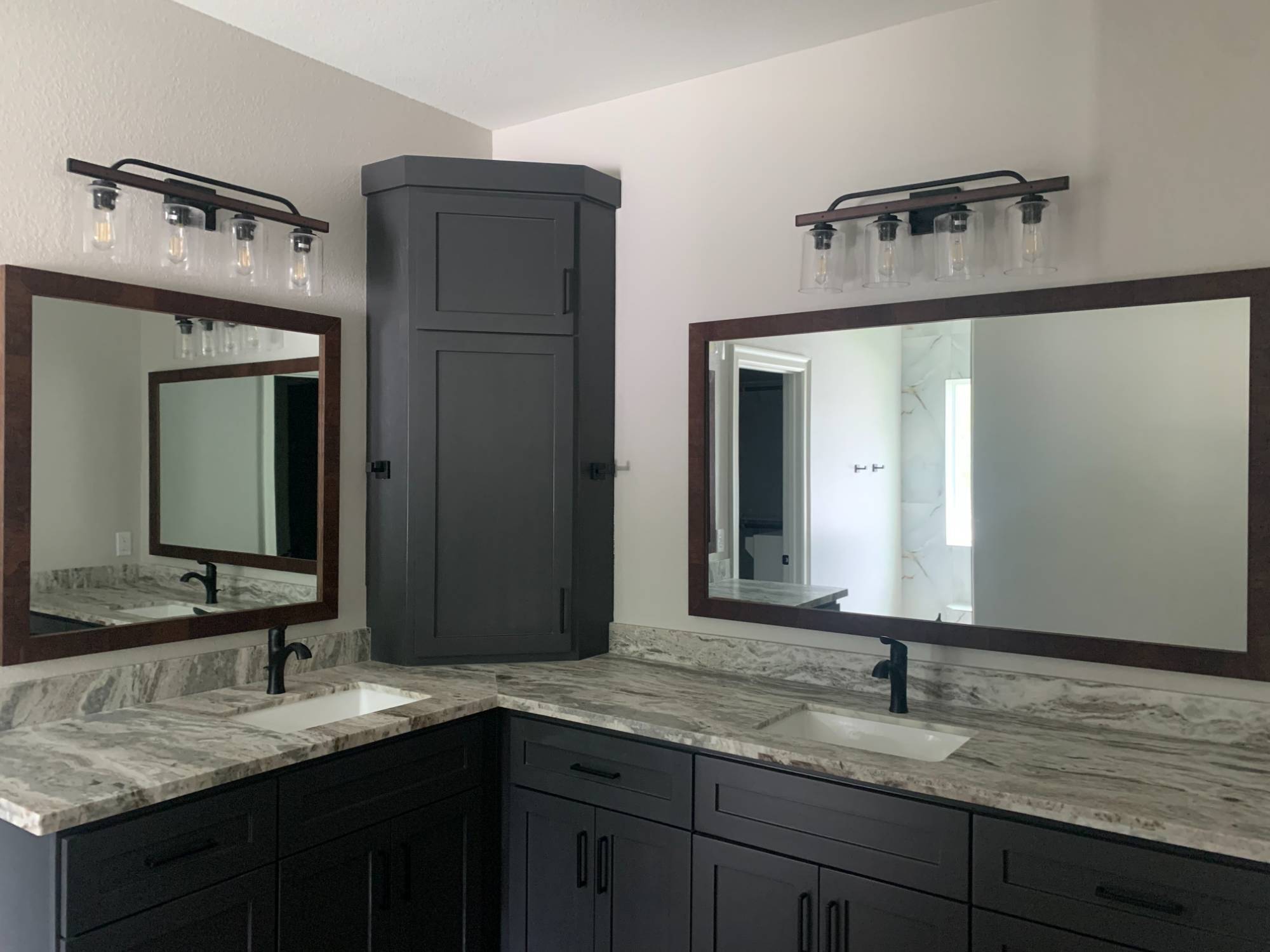 Double vanity bathroom with dark cabinetry and marble countertops by Wonderview Home Services in Magnolia, TX.-optimized
