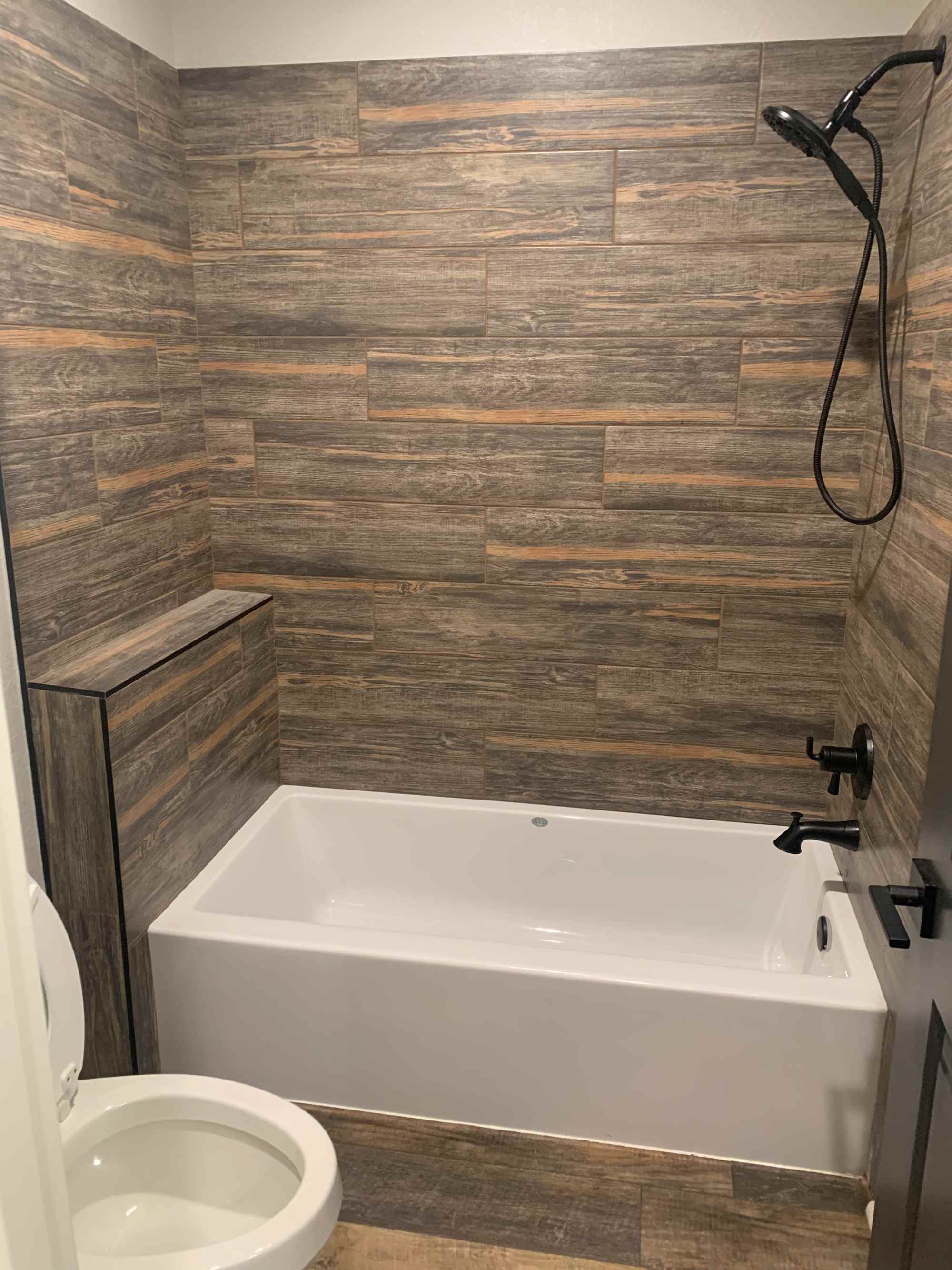Modern bathroom with wood-look tile shower surround and soaking tub by Wonderview Home Services in Magnolia, TX.-optimized