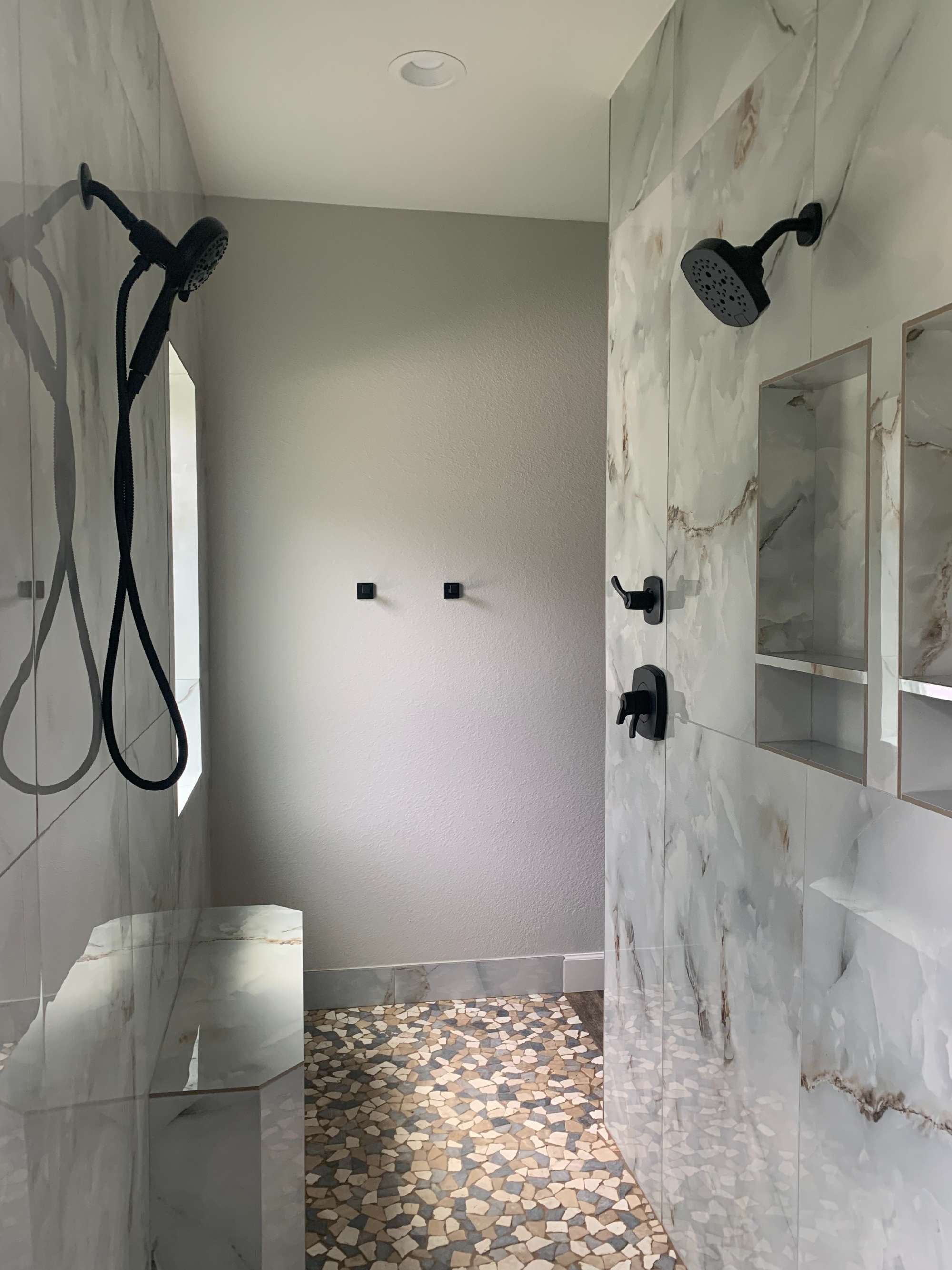 Walk-in marble-look shower with dual showerheads by Wonderview Home Services in Magnolia, TX.-optimized