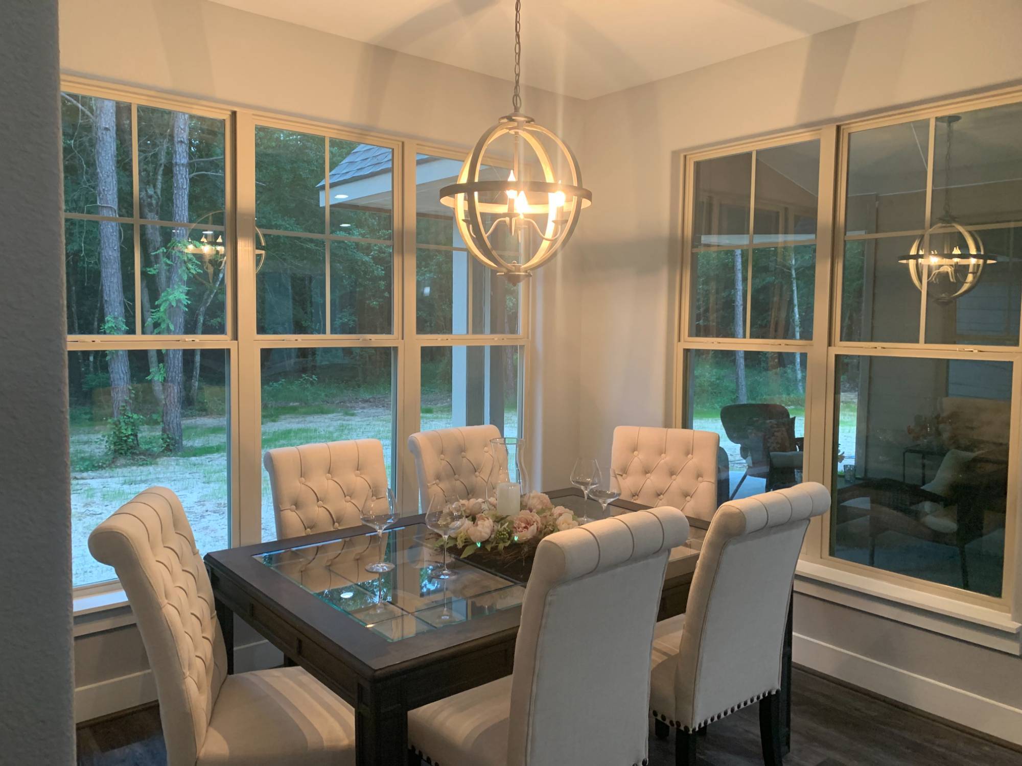 Elegant dining room with large windows and modern chandelier in a custom home by Wonderview Home Services in New Waverly, TX.-optimized